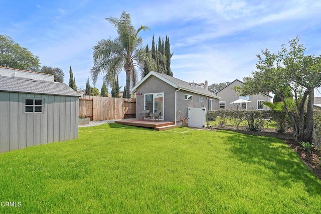 rear view of house featuring a yard, a deck, an outbuilding, a fenced backyard, and a storage unit