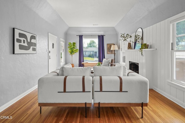 living area with baseboards, wood finished floors, a fireplace, and a textured wall