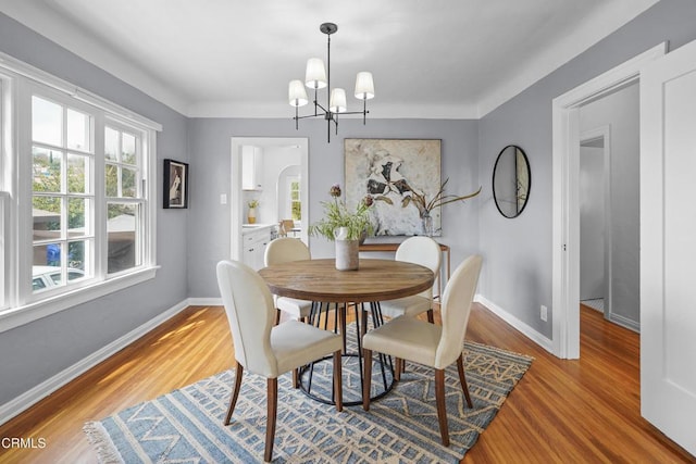 dining area with a chandelier, baseboards, and light wood-style floors