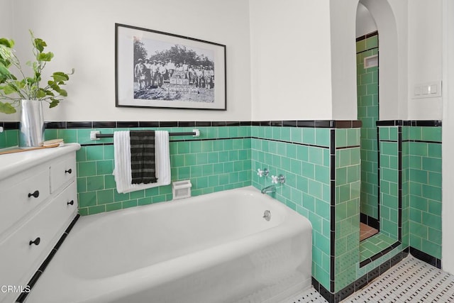 full bathroom with a garden tub, tile walls, and a wainscoted wall