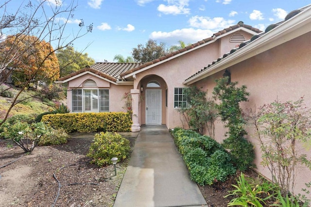 entrance to property with stucco siding and a tiled roof