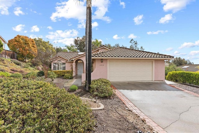 view of front of home with a tile roof, stucco siding, driveway, and an attached garage