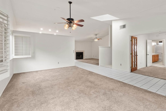 unfurnished living room with carpet floors, lofted ceiling, a fireplace, and tile patterned flooring