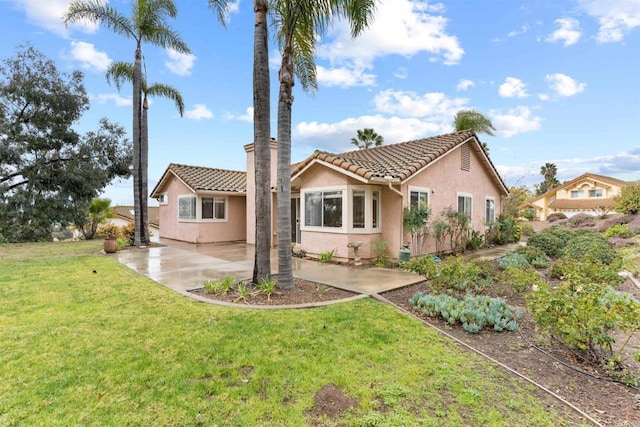 view of front of home featuring a patio, a front yard, a tile roof, and stucco siding