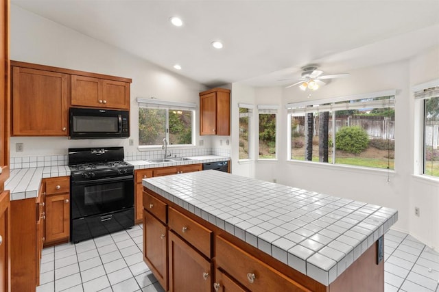 kitchen with brown cabinets, black appliances, a sink, tile countertops, and light tile patterned floors