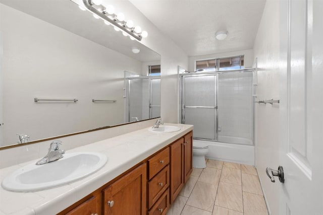 bathroom featuring double vanity, bath / shower combo with glass door, and a sink