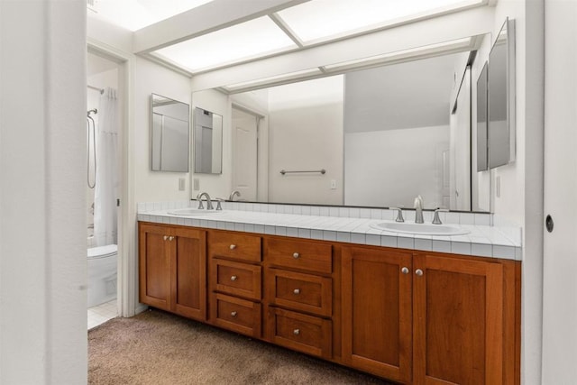 bathroom featuring a sink, a shower with curtain, double vanity, and toilet