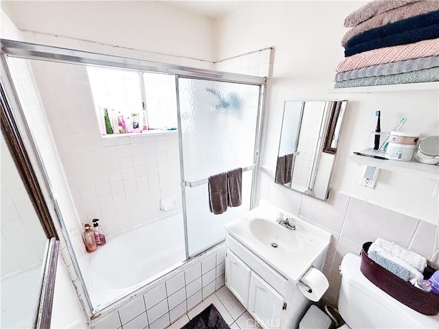 full bathroom featuring tiled shower / bath, toilet, backsplash, tile walls, and vanity