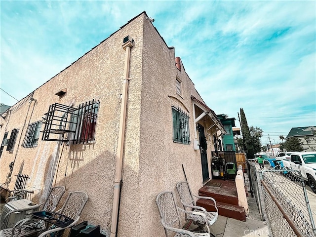 view of property exterior featuring stucco siding and fence