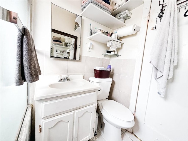 bathroom featuring toilet, tile walls, and vanity