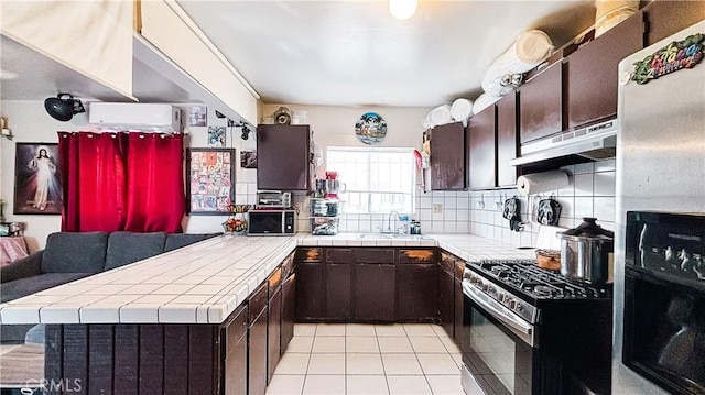 kitchen with under cabinet range hood, a sink, backsplash, tile countertops, and appliances with stainless steel finishes