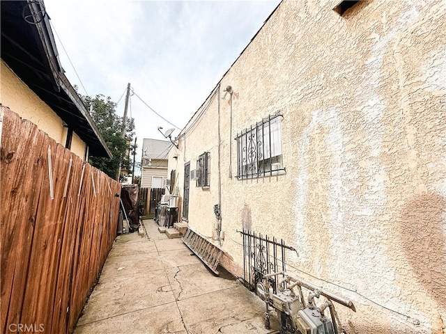 view of property exterior with a patio area, fence, and stucco siding