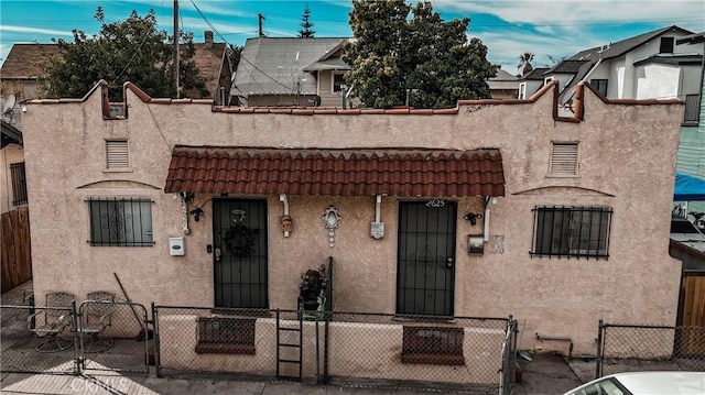 view of front of property with a fenced front yard, stucco siding, and a tile roof