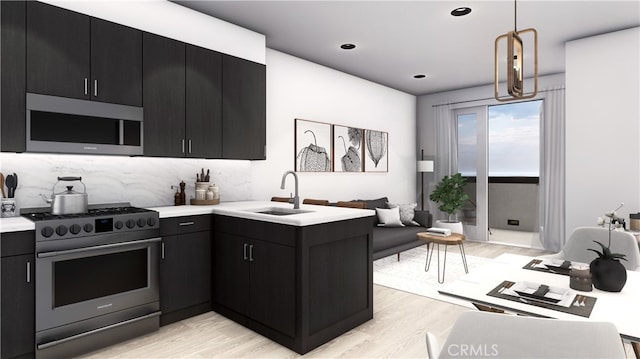 kitchen featuring a sink, light countertops, light wood-style flooring, stainless steel appliances, and dark cabinets