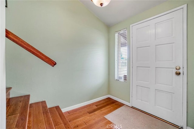 entrance foyer with vaulted ceiling, stairway, wood finished floors, and baseboards