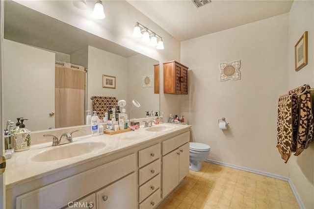 bathroom with a sink, toilet, double vanity, and tile patterned floors