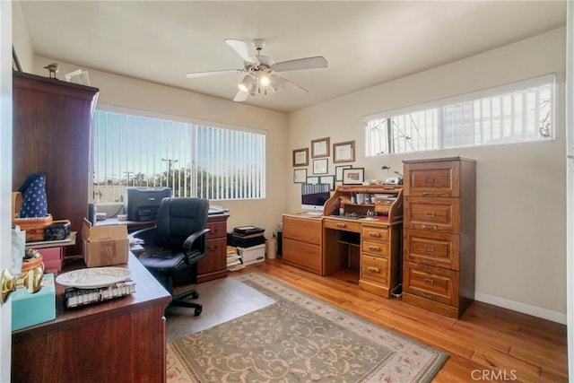 office featuring baseboards, light wood-type flooring, and a ceiling fan