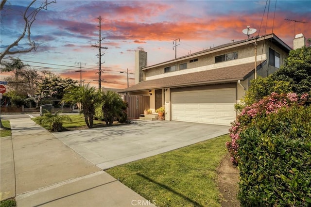 view of front of home with a garage, concrete driveway, a chimney, and stucco siding