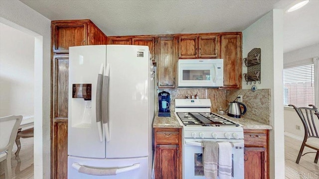 kitchen featuring backsplash, light stone countertops, brown cabinets, white appliances, and a textured ceiling