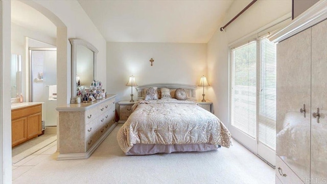 bedroom featuring arched walkways, light carpet, and vaulted ceiling