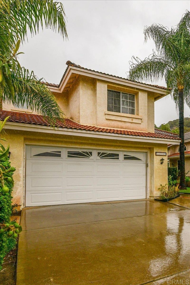 view of front of home with a tile roof, stucco siding, concrete driveway, and a garage