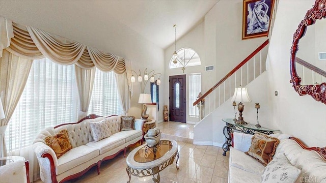 living room with stairway, visible vents, a wealth of natural light, and high vaulted ceiling