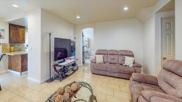 living area with baseboards, lofted ceiling, light tile patterned floors, recessed lighting, and arched walkways