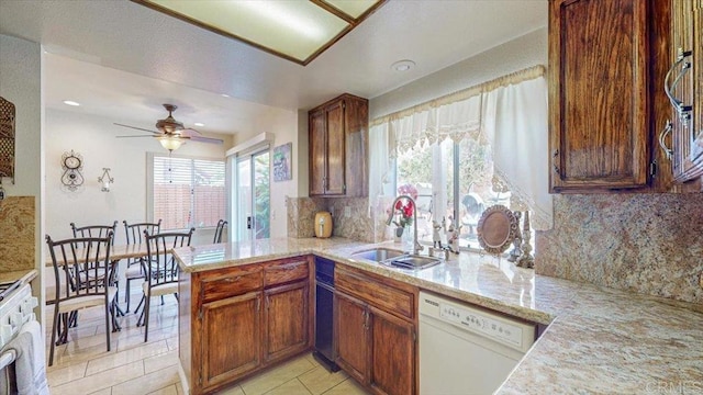 kitchen with a peninsula, light tile patterned flooring, white dishwasher, a sink, and decorative backsplash