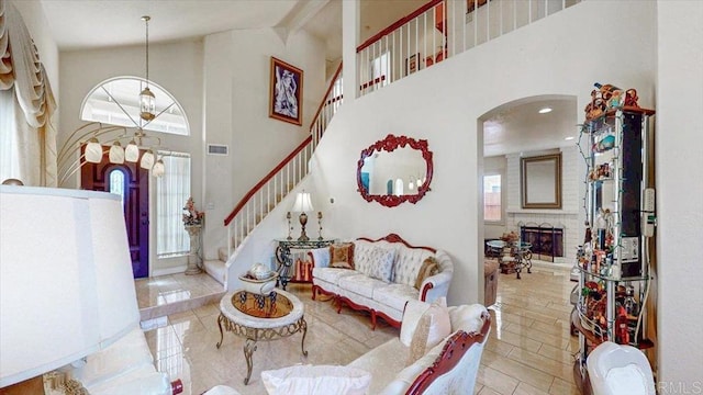 tiled living area with stairway, visible vents, high vaulted ceiling, arched walkways, and a brick fireplace