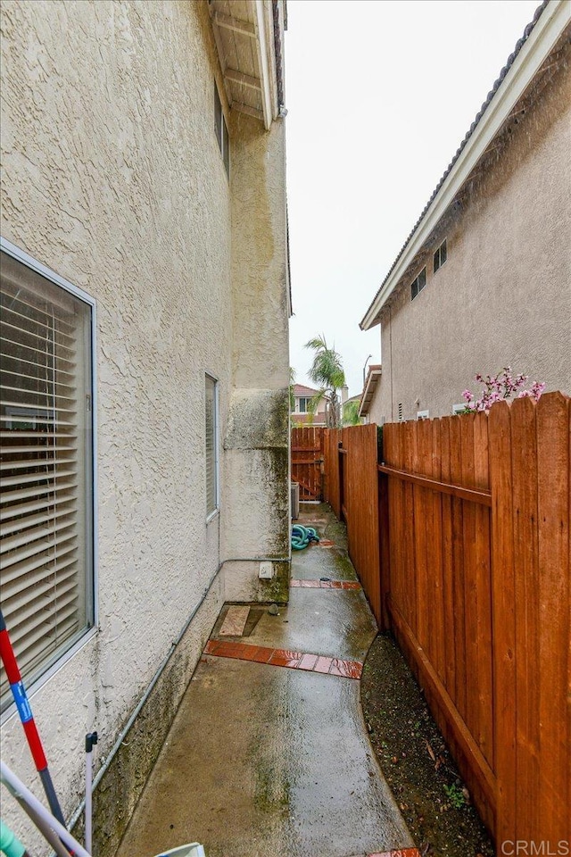 view of side of property with stucco siding, a patio, and fence