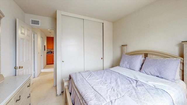 bedroom featuring light colored carpet, visible vents, and a closet