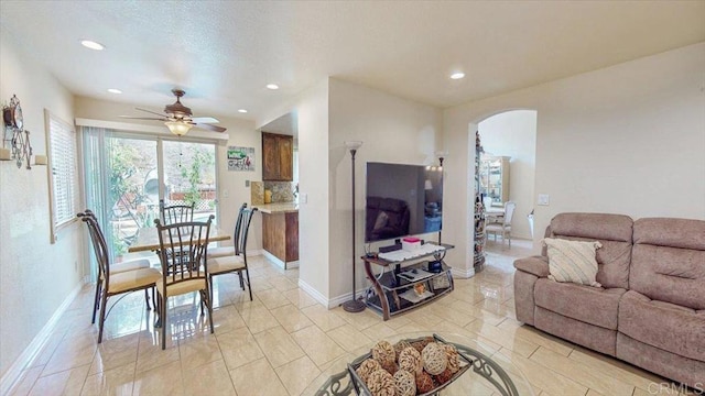 living area with arched walkways, recessed lighting, a ceiling fan, and baseboards