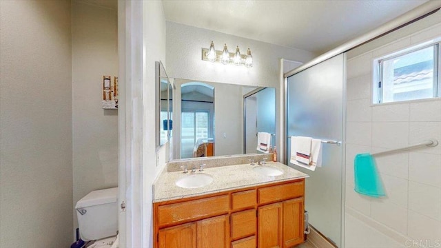 bathroom featuring a wealth of natural light, double vanity, toilet, and a sink