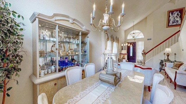 dining space featuring visible vents, high vaulted ceiling, an inviting chandelier, and stairway