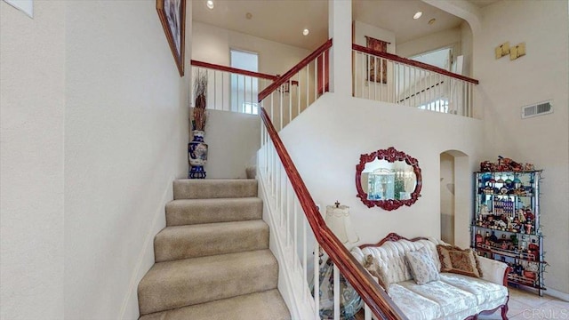 stairway with arched walkways, visible vents, and a high ceiling