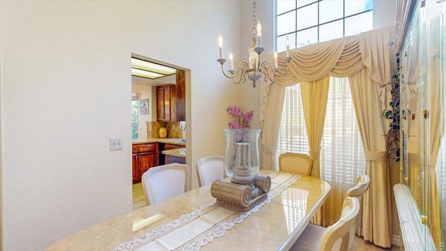 dining room featuring a wealth of natural light, an inviting chandelier, and a towering ceiling