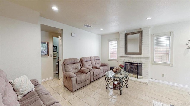 living room with visible vents, recessed lighting, a brick fireplace, and baseboards