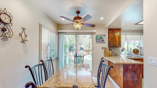 dining area with a ceiling fan, baseboards, and a textured wall