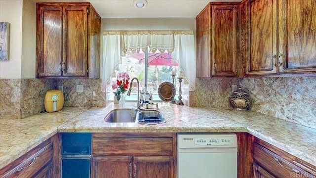 kitchen featuring decorative backsplash, white dishwasher, a sink, and light countertops