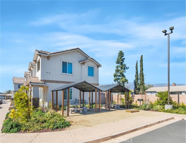 exterior space featuring stucco siding, fence, and a tiled roof