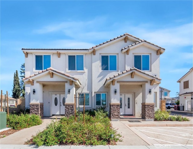 view of front of property featuring stucco siding, stone siding, and fence