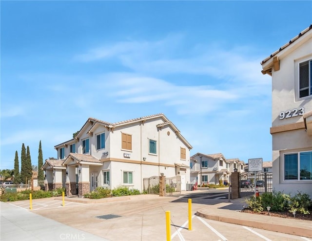 view of street featuring a gate, sidewalks, curbs, a gated entry, and a residential view