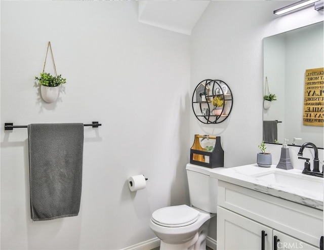 half bath featuring toilet, vanity, and baseboards