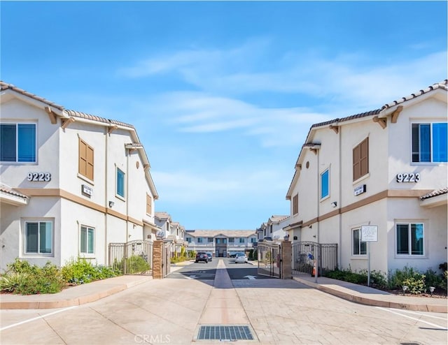 view of road featuring a gate, sidewalks, curbs, a gated entry, and a residential view