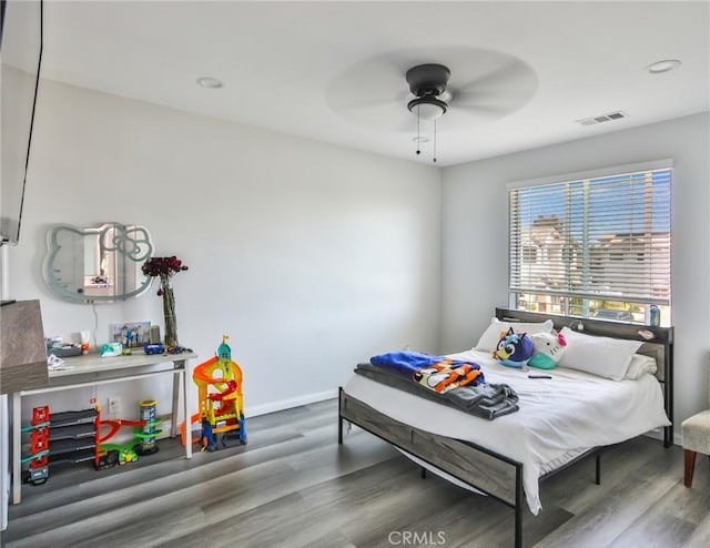 bedroom with visible vents, a ceiling fan, baseboards, and wood finished floors