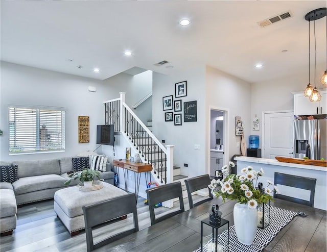 living area with dark wood-style floors, visible vents, recessed lighting, and stairs