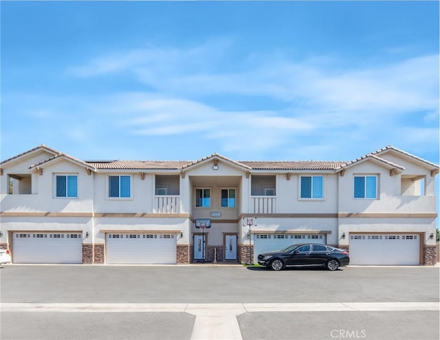 view of front of house featuring a garage, stone siding, and stucco siding