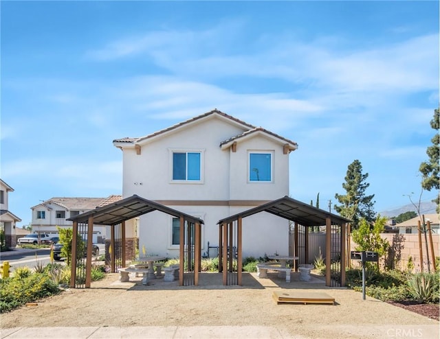 rear view of property with stucco siding and fence