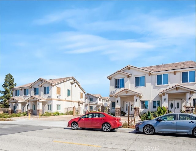 multi unit property with a tiled roof, a residential view, and stucco siding