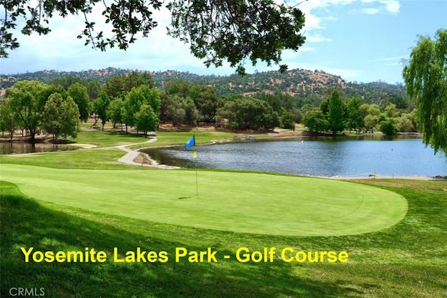 view of home's community featuring view of golf course, a lawn, and a water view